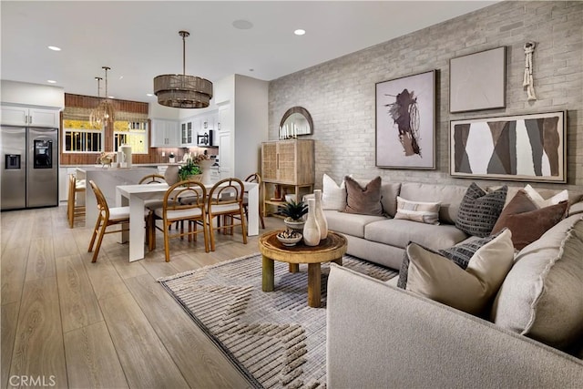 living room featuring recessed lighting, light wood finished floors, and brick wall