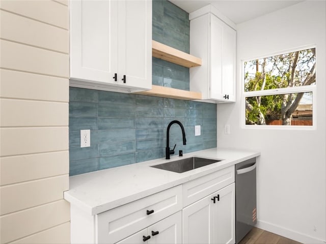 kitchen featuring backsplash, open shelves, dishwasher, a sink, and light stone counters