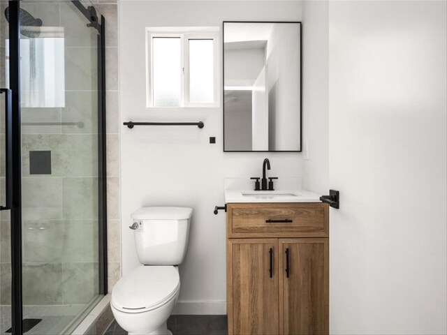 full bath featuring vanity, toilet, baseboards, and a stall shower