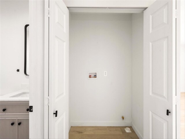 laundry room with laundry area, hookup for a washing machine, light wood finished floors, and baseboards