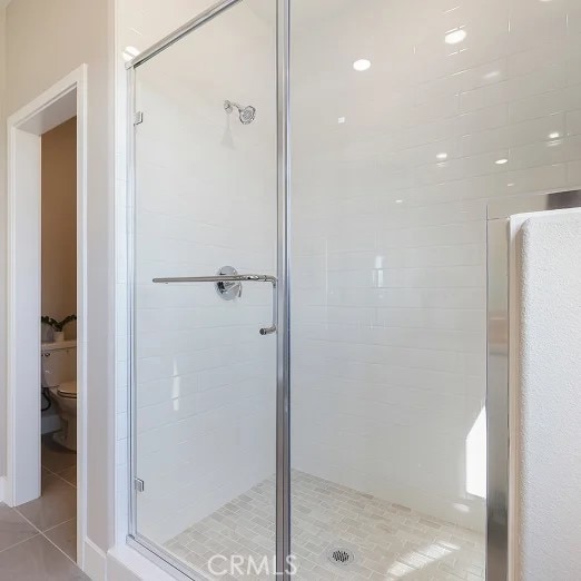 full bathroom featuring tile patterned flooring, a stall shower, and toilet