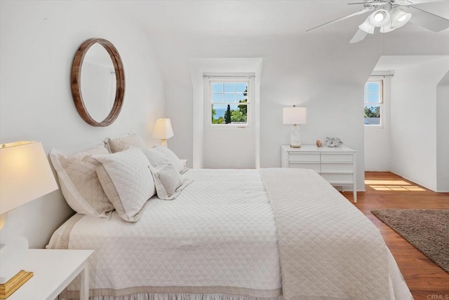 bedroom featuring ceiling fan, wood finished floors, and multiple windows