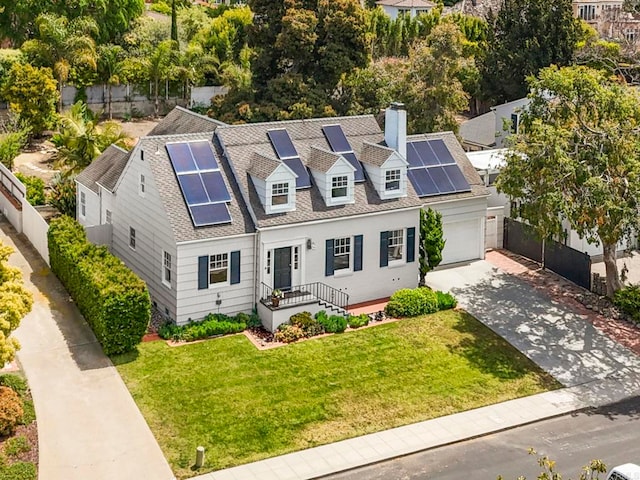cape cod house with driveway, a chimney, a front yard, fence, and roof mounted solar panels