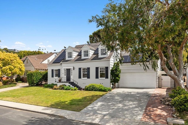 cape cod home featuring a shingled roof, a garage, a front yard, solar panels, and driveway