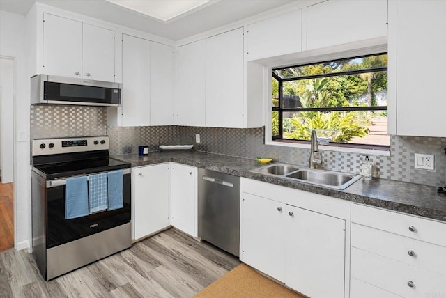 kitchen with a sink, appliances with stainless steel finishes, white cabinets, and light wood-style floors