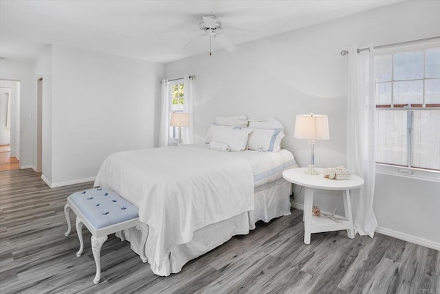 bedroom with a ceiling fan, baseboards, and wood finished floors