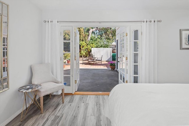 bedroom with french doors, baseboards, wood finished floors, and access to outside