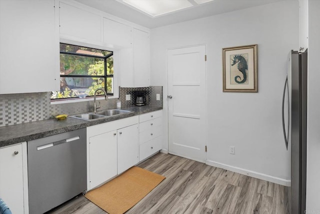 kitchen with light wood-type flooring, a sink, dark countertops, and stainless steel appliances