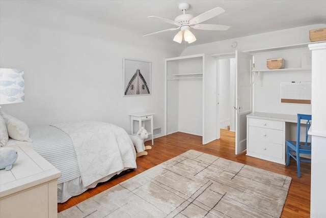 bedroom with a ceiling fan, visible vents, and wood finished floors