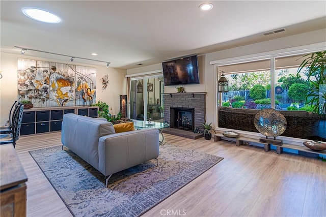 living area with visible vents, recessed lighting, a brick fireplace, and wood finished floors