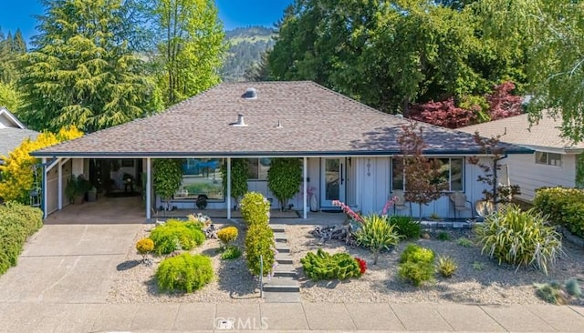 view of front of home featuring board and batten siding, roof with shingles, covered porch, and concrete driveway