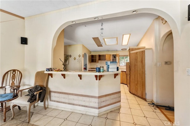 20780 Calle Rocio, Temecula, CA 92590 - kitchen featuring tile counters, a peninsula, a breakfast bar, brown cabinetry, and crown molding