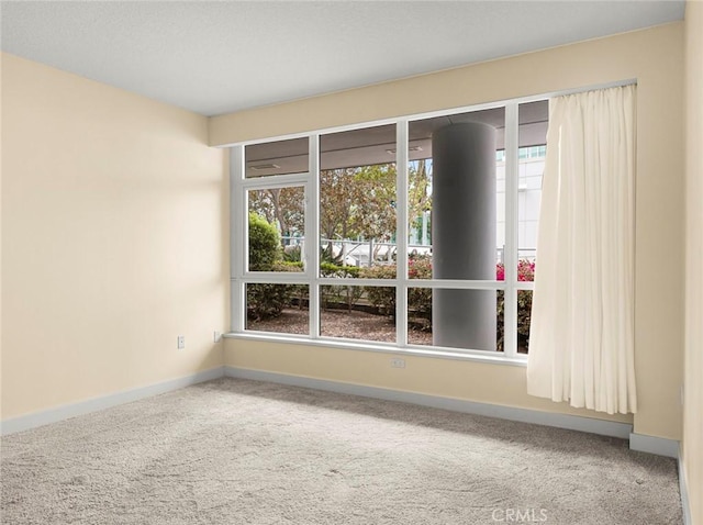 carpeted empty room featuring baseboards and a healthy amount of sunlight