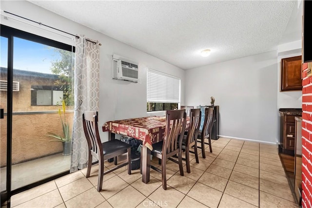 dining space featuring an AC wall unit, baseboards, a textured ceiling, and light tile patterned floors