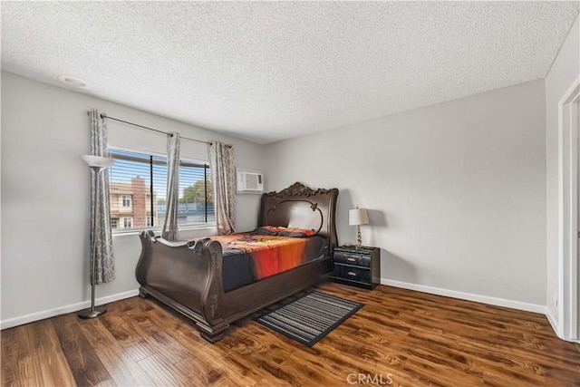 bedroom with baseboards, a textured ceiling, a wall mounted AC, and wood finished floors