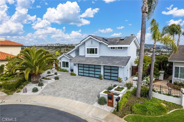 303 Calle Paisano, San Clemente, CA 92673 - view of front of house with decorative driveway, an attached garage, fence, and roof mounted solar panels