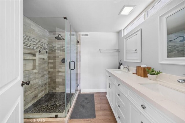 24052 Estacia Ave, Laguna Niguel, CA 92677 - full bath with double vanity, visible vents, a stall shower, wood finished floors, and a sink
