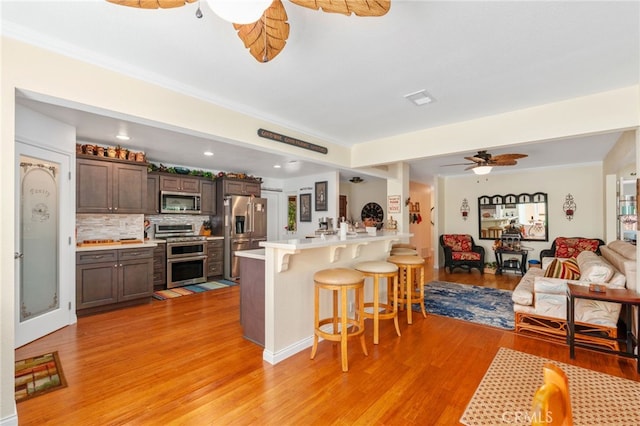1316 Via Ln, Ranchita, San Marcos, CA 92069 - kitchen with a peninsula, a breakfast bar area, light wood-type flooring, light countertops, and stainless steel appliances