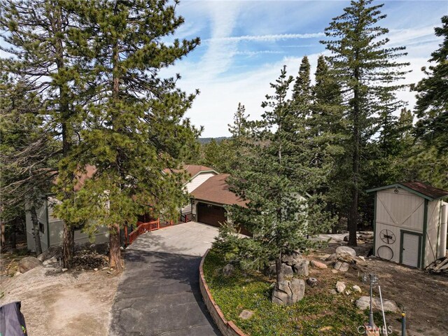 32424 Snowshoe Ln, Running Springs, CA 92382 - view of front facade featuring a storage unit, an outdoor structure, an attached garage, and driveway