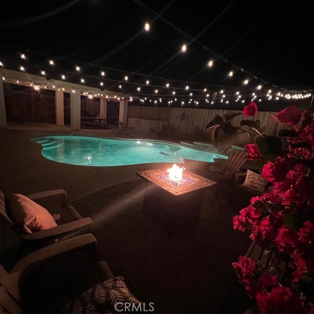 pool at twilight with a fenced in pool, a patio, a fenced backyard, and an outdoor fire pit