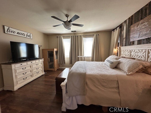 bedroom with visible vents, a ceiling fan, a textured ceiling, and dark wood-type flooring