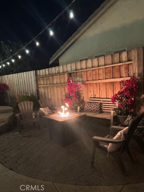 patio at twilight featuring fence, a fire pit, and visible vents