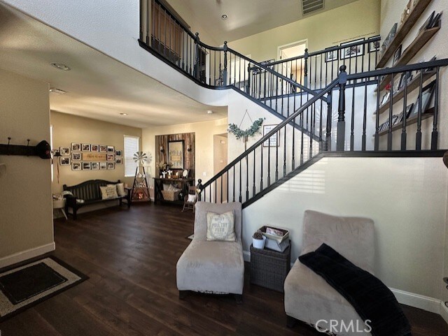 stairway featuring baseboards, a towering ceiling, wood finished floors, and visible vents