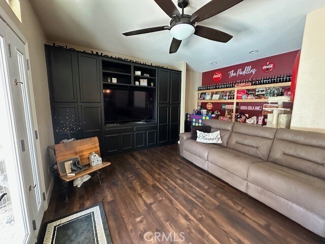 living area with a ceiling fan and dark wood-style flooring