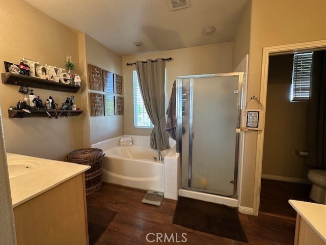 full bathroom featuring a garden tub, visible vents, a shower stall, wood finished floors, and vanity