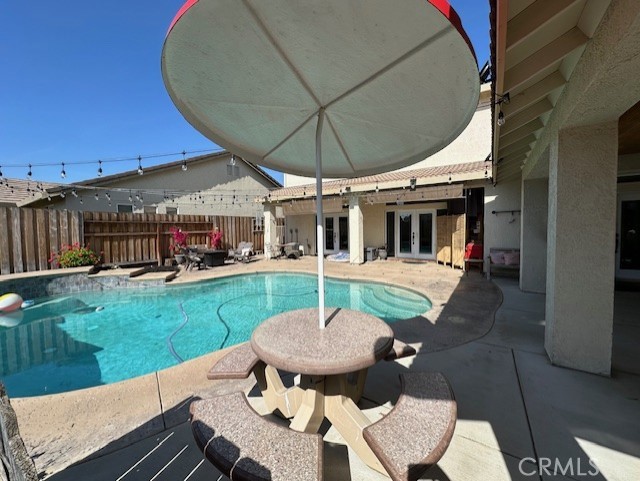 view of pool with a patio, fence, french doors, and a fenced in pool