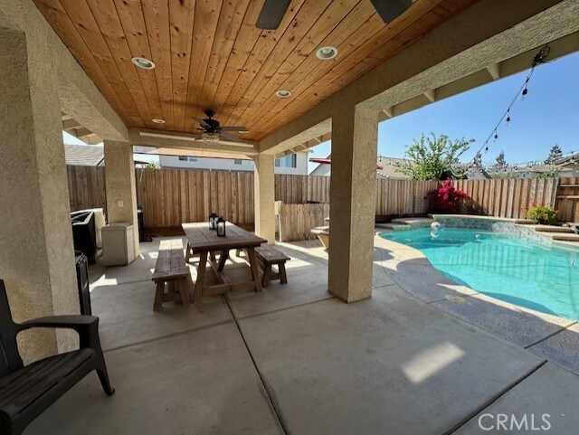 view of swimming pool with a patio, a fenced backyard, a fenced in pool, a ceiling fan, and outdoor dining space