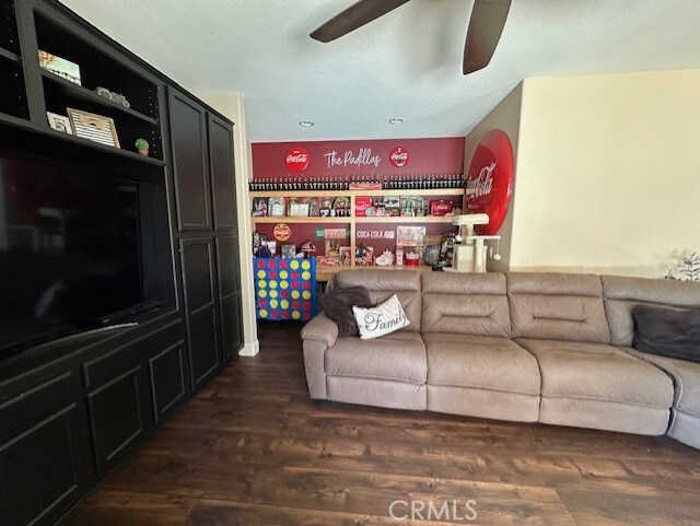 living area featuring ceiling fan and dark wood-type flooring