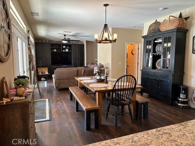 dining space featuring visible vents, ceiling fan with notable chandelier, and dark wood-type flooring