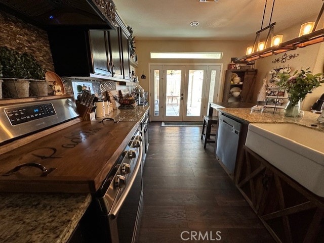 kitchen with light stone counters, dark wood-style floors, french doors, a sink, and appliances with stainless steel finishes