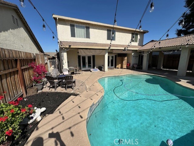 back of property with a fenced backyard, stucco siding, french doors, a fenced in pool, and a patio area