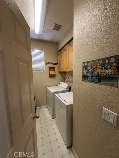 washroom with visible vents, cabinet space, baseboards, light floors, and washer and dryer