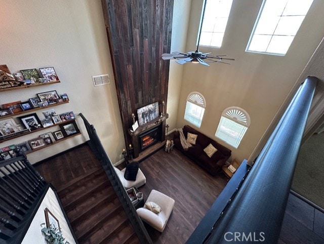 living room with a healthy amount of sunlight, a ceiling fan, a glass covered fireplace, and visible vents