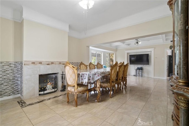 dining space with light tile patterned flooring, a fireplace, crown molding, ceiling fan, and coffered ceiling