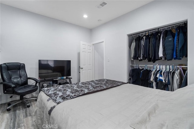 bedroom featuring wood finished floors, a closet, visible vents, baseboards, and recessed lighting