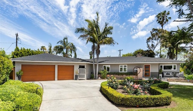 ranch-style home featuring a garage, a chimney, concrete driveway, and stucco siding