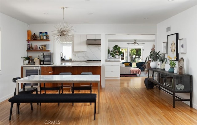 dining space featuring visible vents, light wood finished floors, wine cooler, and ceiling fan