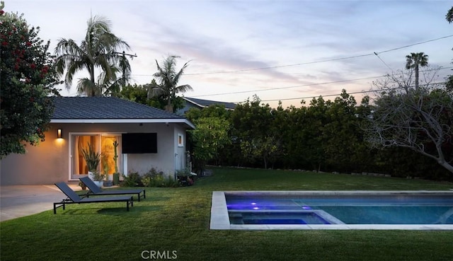 pool with a lawn and an in ground hot tub