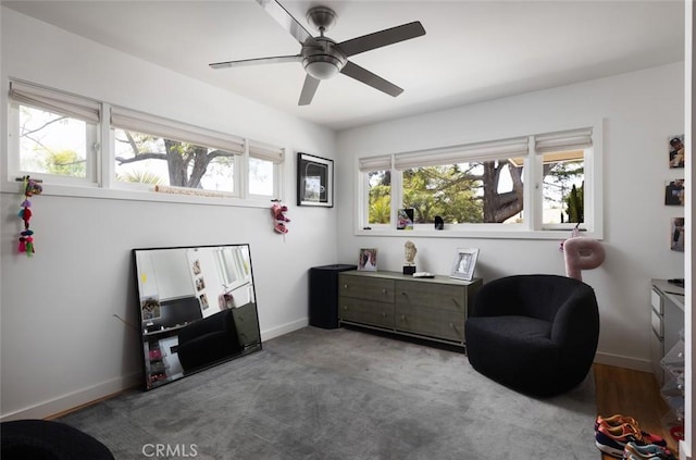 living area with baseboards and ceiling fan