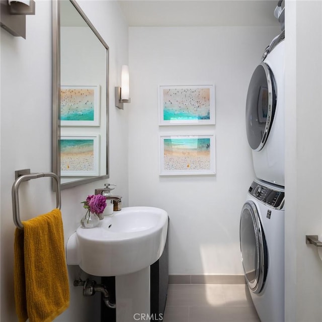 bathroom featuring stacked washer and dryer, baseboards, and tile patterned floors