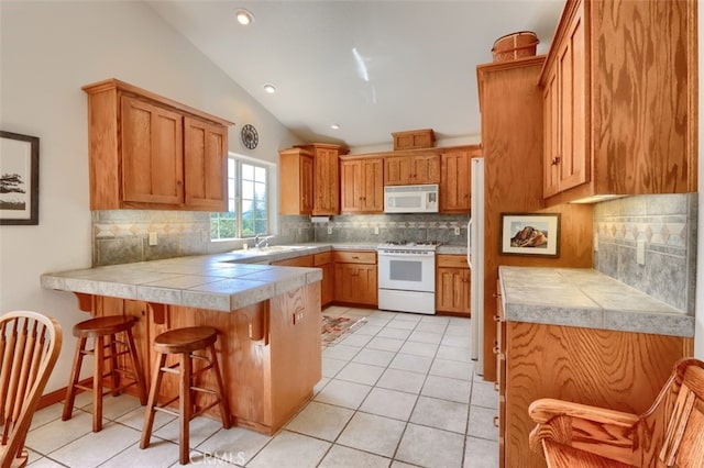 kitchen featuring a peninsula, light tile patterned flooring, white appliances, and a sink