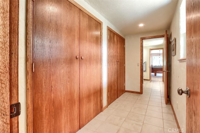 corridor featuring baseboards and light tile patterned floors