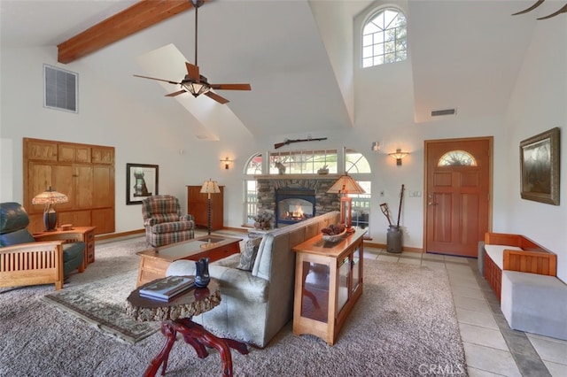 living area featuring visible vents, a ceiling fan, a fireplace, and high vaulted ceiling