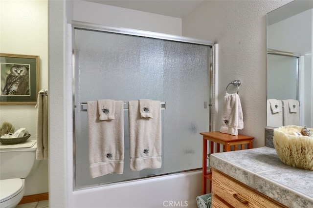 full bathroom featuring vanity, combined bath / shower with glass door, and toilet