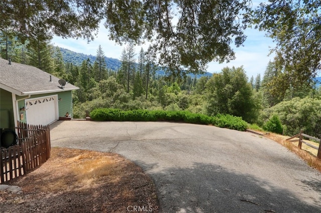 exterior space with a forest view, driveway, and a mountain view