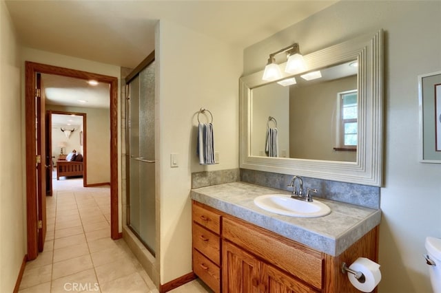 full bathroom featuring vanity, toilet, baseboards, tile patterned floors, and a stall shower